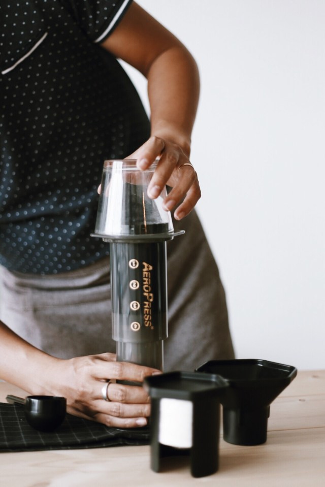 Đặt chiếc cốc thuỷ tinh lên trên đỉnh của Aeropress, rồi nhanh chóng lật ngược 180 độ.